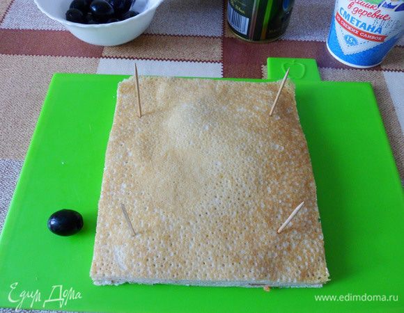 Придадим блинам прямоугольную форму. Для лучшего фиксирования слоев скрепим края прямоугольника шпажками. Маслинка поможет мне помнить о размере канапе.
