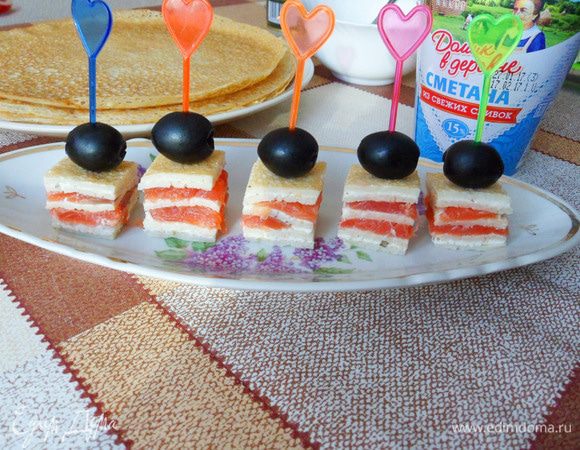 Скрепляем шпажкой блинчики с семгой и маслинкой.