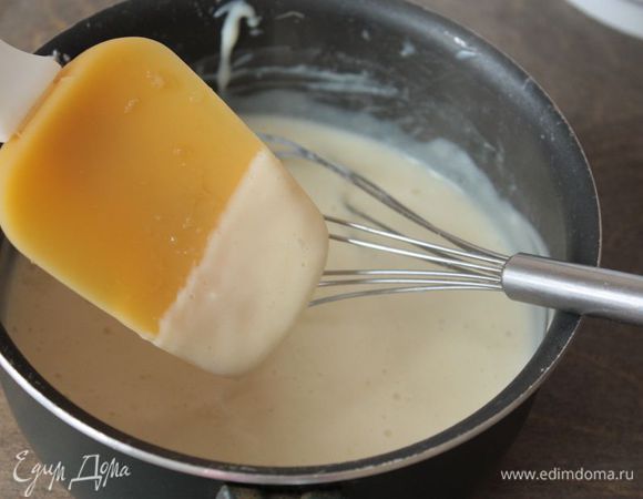 Настал черед муссового крема. Его мы будем готовить в несколько этапов. Для начала сварим заварной крем: 300 мл молока «Домик в деревне» разделите на две части. Одну часть взбейте с яйцами, сахаром, крахмалом и ваниль. Вторую часть поставьте на огонь и, как только она закипит, осторожно влейте в яичную смесь. При переливании горячего молока не забывайте помешивать! Получившийся крем перелейте обратно в сотейник и снова поставьте на средний огонь, после чего варите, помешивая, до загустения. Готовый заварной крем снимите с огня и накройте пищевой пленкой, чтобы крем остыл и не заветрился.