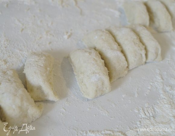 Поверхность обильно присыпать мукой и выложить картофельное тесто. Сформировать колбаску и нарезать на небольшие кусочки. 