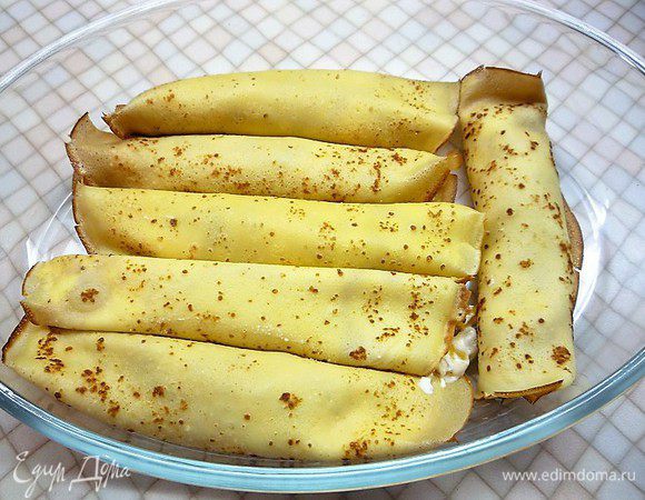 Скатываем блинчики в плотные рулеты и выкладываем в форму для запекания.