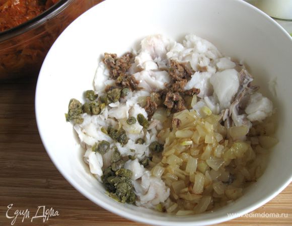 Приготовить рыбную начинку. Использовала для нее замороженное филе трески. Его надо немного оттаять и отварить в небольшом количестве подсоленной воды. Положить на дуршлаг, дать просохнуть, разобрать на пластины или маленькие кусочки. Добавить обжаренный лук, порезанные каперсы и порезанные анчоусы, перец.