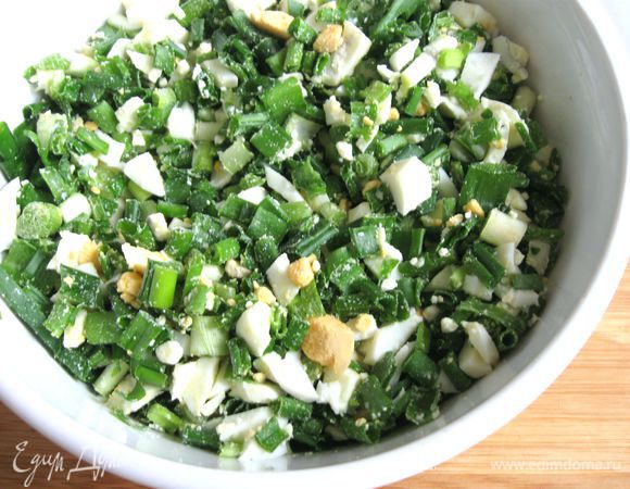 Приготовить начинку из зеленого лука и яиц. Лук помыть, обсушить, мелко порезать, яйца порезать. Объединить, посолить, перемешать.