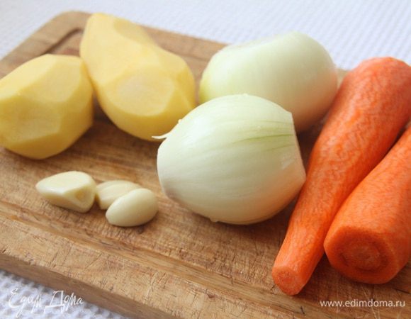 Подготовить овощи: почистить 2 моркови, 2 луковицы, 2 картофелины и 3 зубчика чеснока.