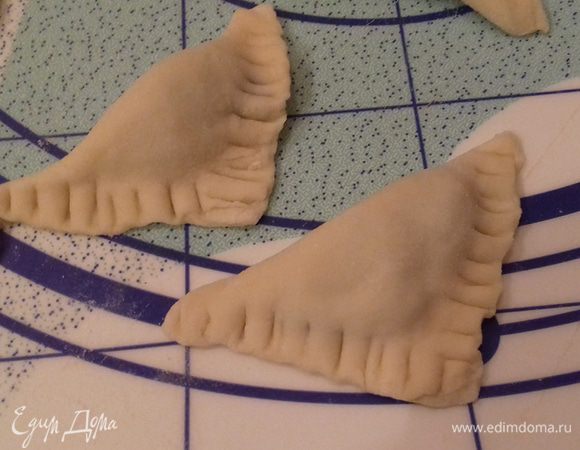 Залепляем пельмени треугольником, по краю для крепости и резного рисунка прижимаем дополнительно вилкой. 
Повторяем до полного использования теста и начинки.
