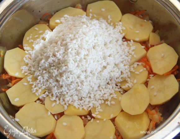 На картофель выложить слой промытого риса.