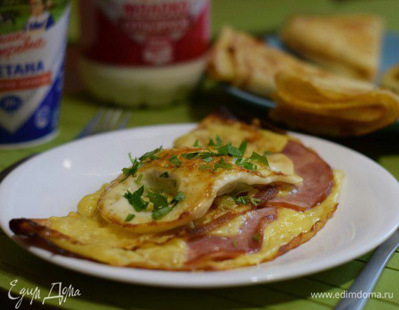 Тем временем поджарить яйца и выложить их на уже готовый блин. Посыпать зеленью.