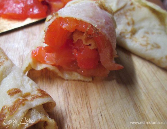 В каждый блин кладем кусочки лосося, сворачиваем пополам. Затем заворачиваем половинку блина с начинкой от внешнего края внутрь и скрепляем шпажкой.