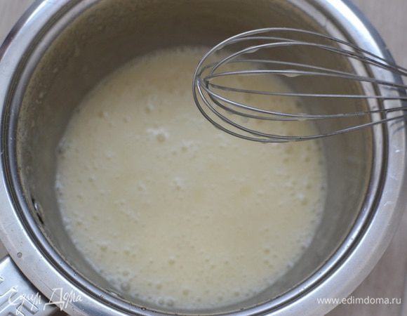 Когда масло равномерно распределится по карамели, влить горячие сливки «Домик в деревне», продолжая взбивать.