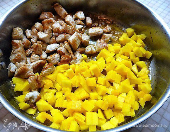 Выкладываем на сковороду мясо индейки и манго, тушим на слабом огне без крышки 3 минуты.