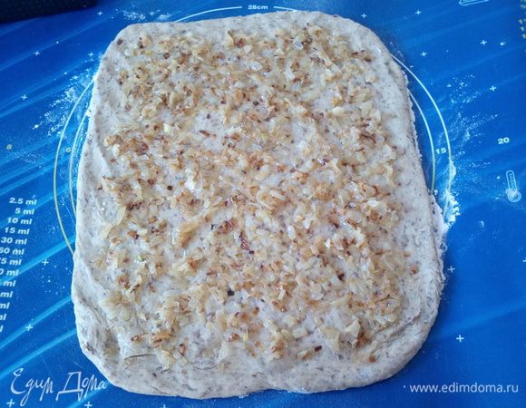 На рабочей поверхности раскатываем тесто в пласт. Выкладываем обжаренный лук.