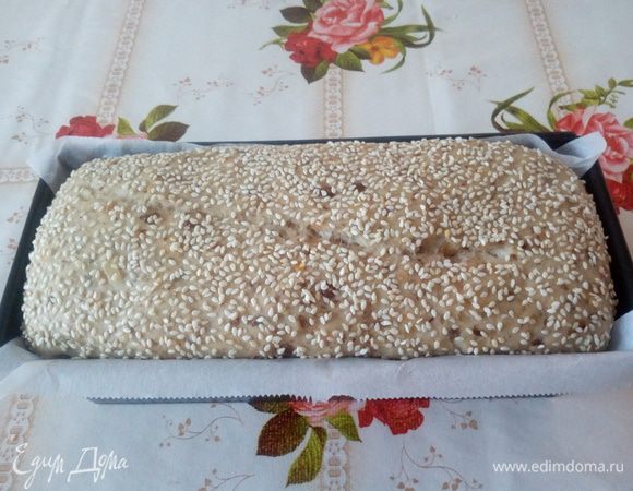 Смазываем поднявшееся тесто теплой водой и посыпаем кунжутом. Помещаем форму в разогретую духовку и выпекаем 30 — 40 минут при 180°С.