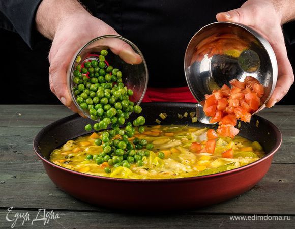 Влить бульон, добавить зеленый горошек и помидоры. Довести до кипения, накрыть крышкой или фольгой и переставить в духовку. Готовить 30 — 40 минут, пока рис не станет мягким, и большая часть жидкости не впитается.