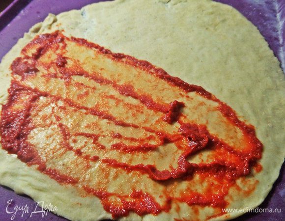 Раскатать половину теста в круг (25 см в диаметре), намазать томатной пастой.