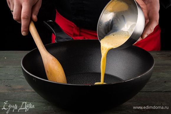 Рис откинуть на дуршлаг, чтобы полностью стекла вся вода. Тем временем в емкости взбить яйцо со щепоткой соли и обжарить его на отдельной сковороде, размешивая лопаткой, чтобы получились кусочки.