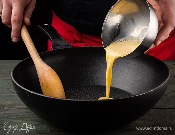 Рис откинуть на дуршлаг, чтобы полностью стекла вся вода. Тем временем в емкости взбить яйцо со щепоткой соли и обжарить его на отдельной сковороде, размешивая лопаткой, чтобы получились кусочки.