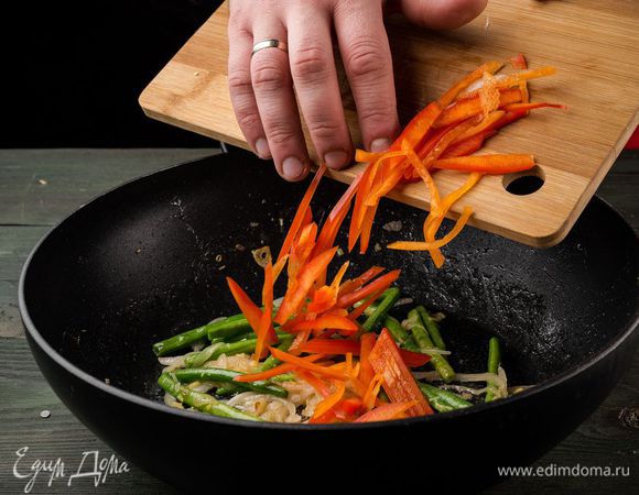 Ставим сковороду-вок на сильный огонь, наливаем масло и обжариваем в нем чеснок, яйцо, имбирь до золотистого цвета. Добавляем болгарский перец. Далее кладем лук и стручковую фасоль. Немного обжариваем.