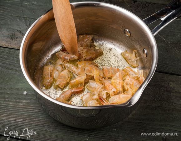 Креветки отварить и почистить (панцири, головы и хвостики не выбрасывать). В небольшой кастрюле растопить сливочное масло и выложить панцири, головы и хвостики креветок.
