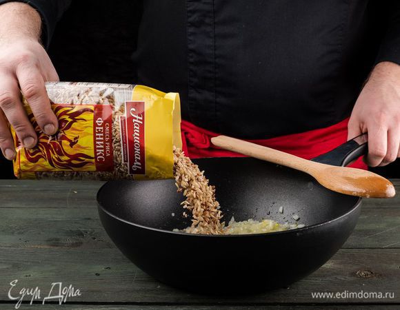 В тяжелой глубокой сковороде разогреть оливковое масло и обжарить лук до прозрачности, всыпать смесь риса Феникс ТМ «Националь» и, помешивая, обжаривать около минуты, пока он не станет прозрачным.