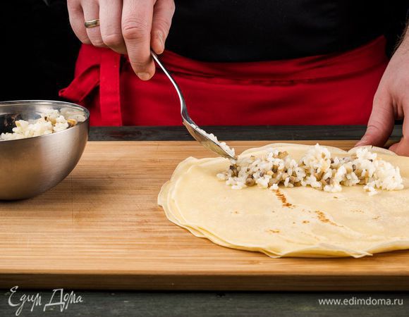 Когда все блины будут пожарены, поместите на середину каждого блинчика начинку, скатайте рулетики и выложите в форму для запекания.