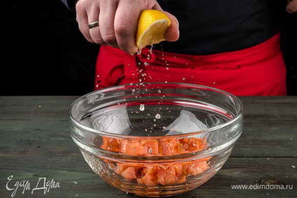 Рыбу нарезать кубиками размером 1 — 2 см, уложить в глубокую посуду, добавить сок половинки лимона, оливковое масло, по щепотке соли и перца.