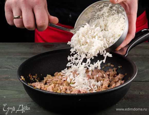 Лук мелко нарезать, обжарить до золотистого цвета на растительном масле, добавить рис, тунца и потушить 2 минуты. 