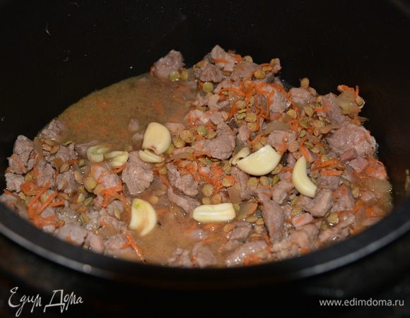 Выключить режим «Жарка». Добавить зеленую чечевицу ТМ «Националь», морковь, чеснок, толченые в ступке специи (кориандр, перец), сушеный чеснок и перемешать. Влить 380 мл кипяченой воды или куриного бульона. Готовить в режиме «Тушение» 40 минут.