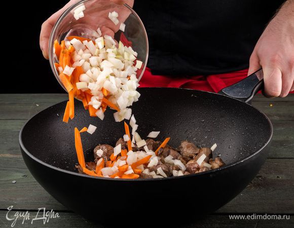 Морковь и лук очистить и нарезать, выложить в жаровню к мясу, обжарить. 