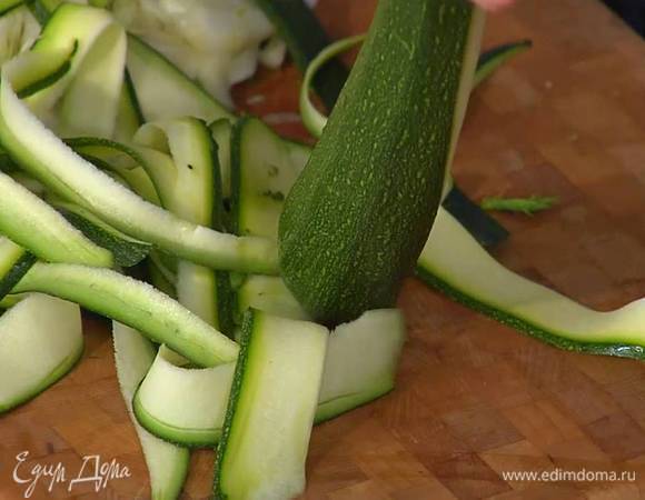 Цукини нарезать вдоль тонкими полосками — можно воспользоваться овощечисткой.