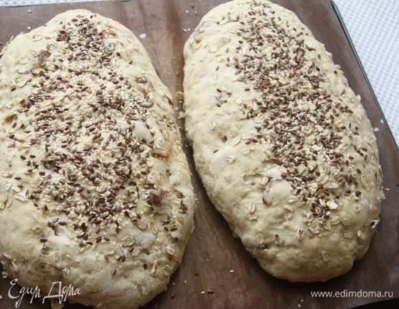 Духовку поставить разогреваться на 190°С вместе с противнем. Поверхность батонов смазать молоком (1 ст. л.), присыпать семенами льна и кунжута.