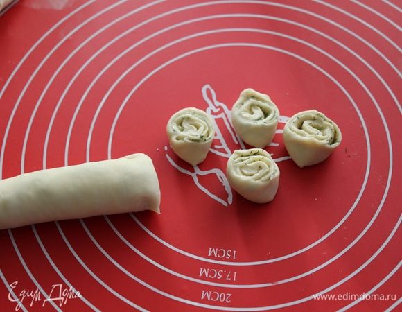 Тесто раскатать в пласт, нанести масляную начинку, свернуть тесто в рулет, затем нарезать его на небольшие кусочки.