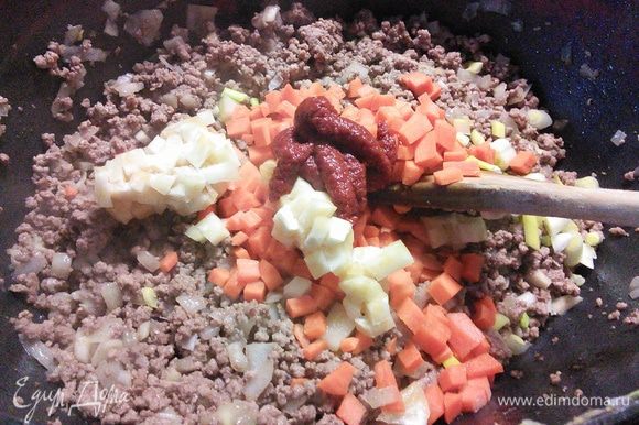 Добавить сельдерей (у меня кусочек корневого сельдерея) и морковь, томатную пасту и еще несколько минут обжарить вместе с мясом.