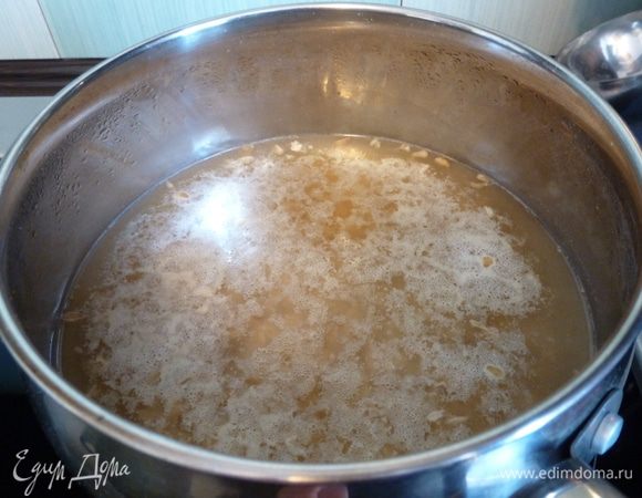 Овсяные хлопья от ТМ «Националь» зальем водой. Оставим кастрюлю на сутки при комнатной температуре. За это время должно начаться брожение, это необходимо для настоящего овсяного киселя! На фото видно, что на поверхности образовалась пена, значит, процесс брожения пошел. Возможно, придется подождать больше по времени, это зависит от температуры воздуха. Брожение придаст овсяному киселю необходимый кисловатый вкус. 