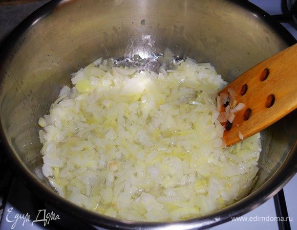 В кастрюле разогреть оливковое масло, обжарить до мягкости мелко нарезанный лук.