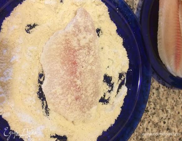 Кукурузную муку смешать с солью и белым перцем. Обвалять рыбу в муке.