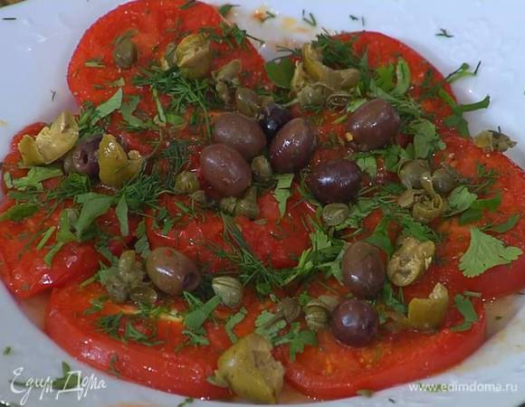 Каперсы и оливки измельчить руками и посыпать помидоры с зеленью.