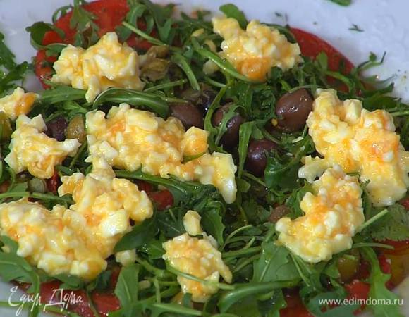 Отваренные яйца почистить, размять вилкой и выложить на помидоры с руколой.