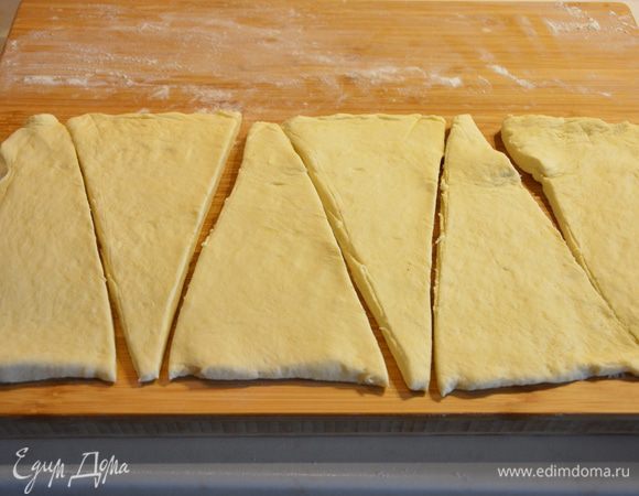 Раскатать одну часть теста в длинный пласт и разделить на треугольники, как на картинке. 6 треугольников с одной половинки, 6 — с другой. Всего 12 круассанов.