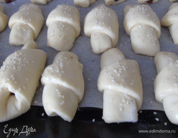 Выкладываем на застеленный пергаментом противень, накрыв салфеткой, даем подойти 30 минут. Затем смазываем желтком, смешанным с 1 ст. л. молока, и присыпаем кунжутом.