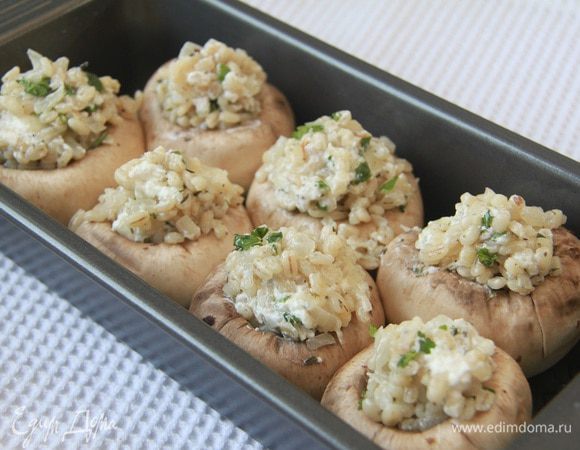Форму смазать маслом. Наполнить шампиньоны начинкой из перловой крупы с сыром. Выпекать в предварительно разогретой до 200°С духовке 15 минут. 