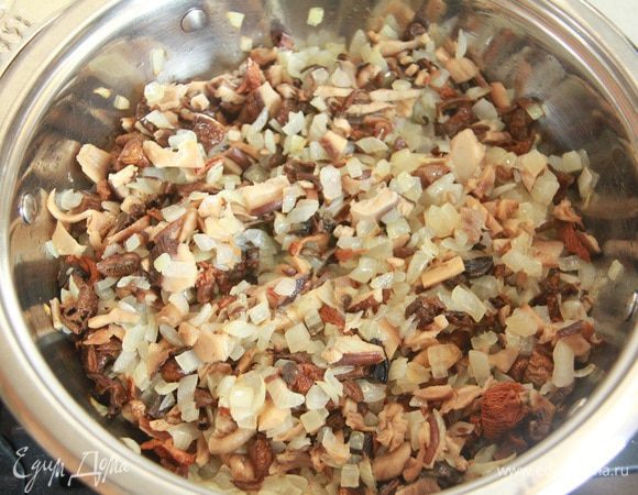 Добавить к луку сушеные грибы, обжаривать еще пару минут.