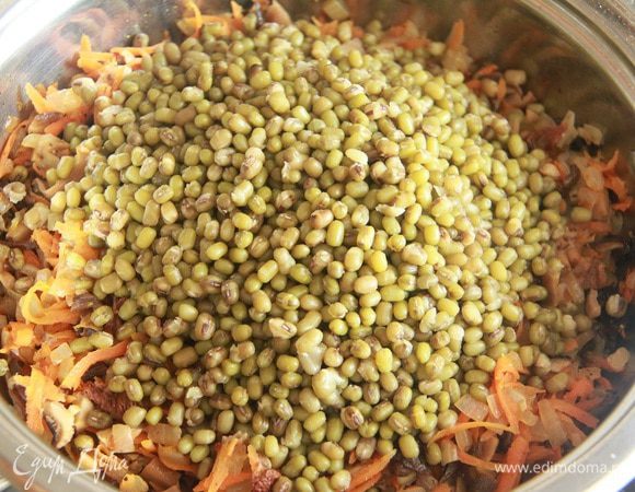 Добавить отварной маш, овощной бульон и настой сушеных грибов, томить на слабом огне 10 минут.