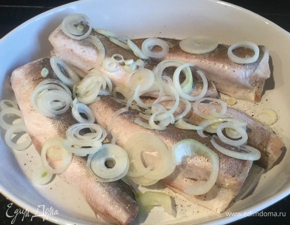 Лук нарежьте кольцами и выложите на хека. Сбрызните лимонным соком.
