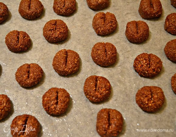 Затем от теста отщипывайте по маленькому кусочку, формируйте шарики и  выкладывайте на слегка смазанный растительным маслом пергамент. Тыльной стороной ножа сделайте по центру шарика небольшие углубления, с боков немного прижмите тесто, имитируя форму кофейного зерна. Поставьте противень в разогретую до 180-200°С духовку и выпекайте печенье 20-25 мин.