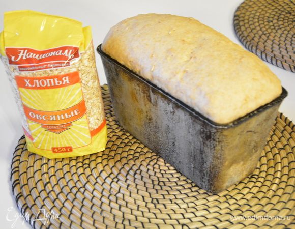 Убрать в теплое место на 30-45 минут.  Смазать хлеб подогретым медом и посыпать овсяные хлопья. Выпекать в хорошо разогретой духовке при 170-180°С 40-50 минут. 