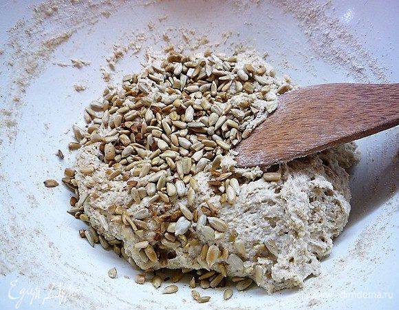 Добавляем обжаренные на сухой сковороде подсолнечные семечки, замешиваем тесто в чашке. Тесто будет липким, но муку досыпать не нужно, так как манная крупа возьмет в себя жидкость, и тесто станет эластичным.