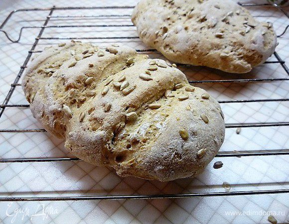 Духовку нагреваем до 200°С, на нижний уровень ставим металлическую емкость, наливаем в нее стакан горячей воды. Подошедший хлеб выпекаем на среднем уровне в течение 15 минут, затем емкость с водой убираем и выпекаем хлеб еще 20 минут. Готовый хлеб остужаем на решетке.