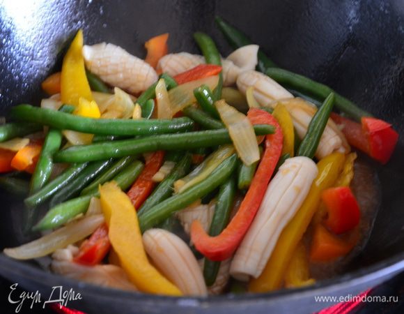 Выложить кальмары и полить соусом, перемешать. Жарить еще 2 минуты, постоянно помешивая.