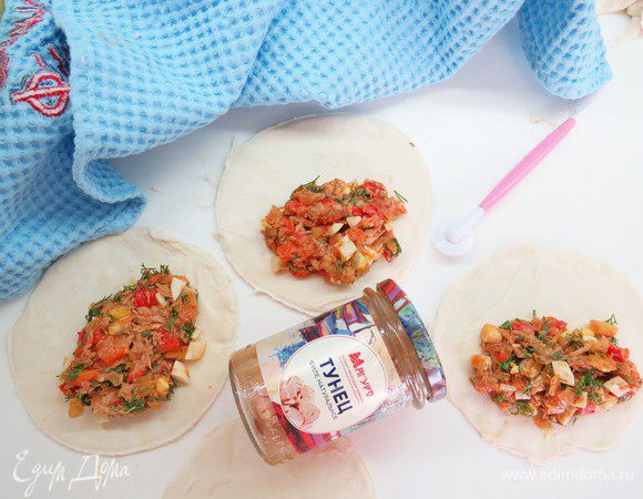 Берем пласт предварительно размороженного теста, вырезаем кружочки нужного диаметра. Кладем начинку на одну половинку кружка и накрываем сверху второй половиной.