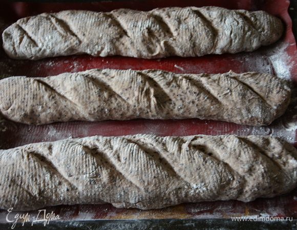 Перевернуть багеты на противень, застеленный пергаментом или силиконовым ковриком, сделать надрезы. 